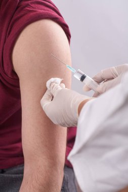Doktorun elleri çok yakın. Doktor kişiye bir enjeksiyon yapar. Mevsimlik aşı. İnokülasyon. Coronavirüs.