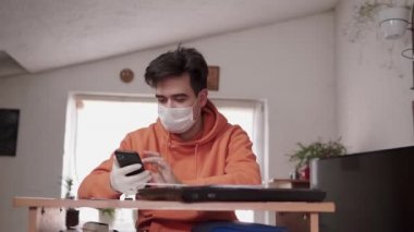Koruyucu maske takan genç adam lastik eldiven kullanıyor. Akıllı telefon haberleşmesi kullanıyor. Hastanede haberleşme işi, virüslerden korunma ve covid-19 salgını kullanıyor.