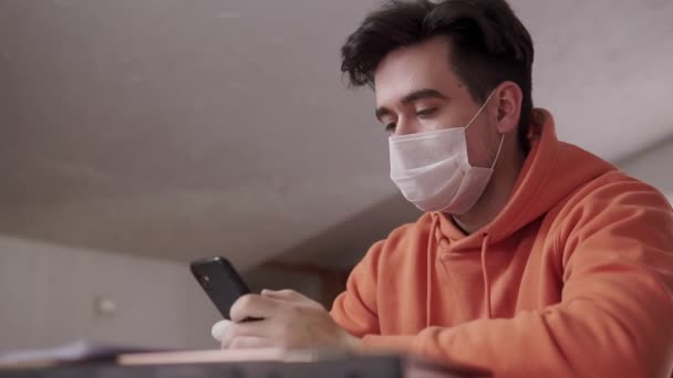 保護マスクのゴム手袋を身に着けている若い男は、病院でのスマートフォンの読書ニュース通信作業を使用しています,ウイルスやcovid-19パンデミックから保護 — ストック動画