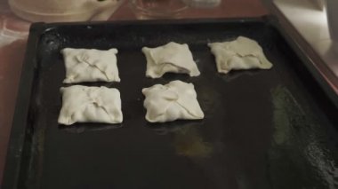 Kadın mutfakta elmalı turta pişiriyor, hamuru bir rulo halinde çeviriyor, elleri yakın, yandan bakıyor..