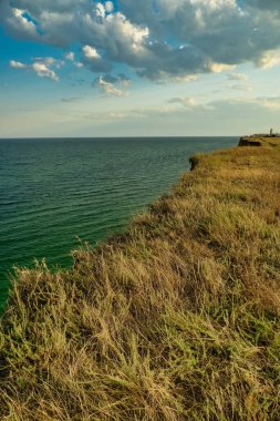 Denizin üzerinde güzel bir gün batımı, suda yansıması, gökyüzünde görkemli bulutlar