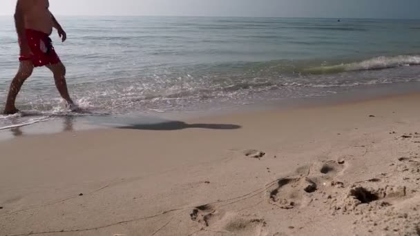 Man Shorts Promenader Längs Stranden Lämnar Fotspår Klart Vatten Begreppet — Stockvideo