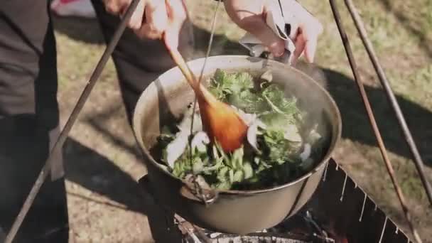 肉与米和蔬菜一起在木桩上的大锅里烹调 厨师用威士忌酒搅拌配料 制作毛皮片 — 图库视频影像