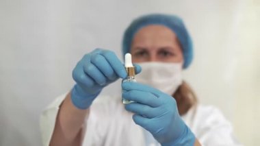 Aşı virüsü. Coronavirus konsepti. Doktor elinde bulanık mavi bir arka plan üzerinde aşısı olan bir ampul tutuyor. Virüs koruması. Soğuk algınlığı ve grip.