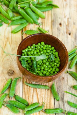 kahverengi çanak içinde closeup yeşil bezelye, ahşap masa üzerinde.