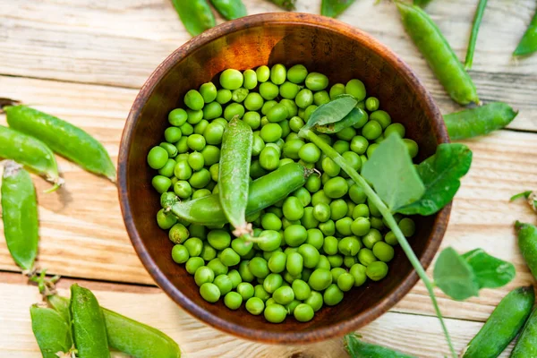 Primer Plano Guisantes Verdes Plato Marrón Sobre Mesa Madera —  Fotos de Stock