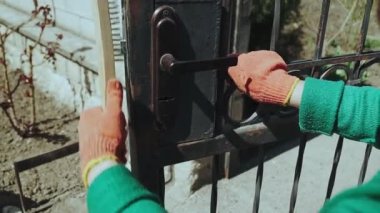Usta paslı metal çiti temizler.