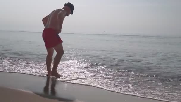 Hombre Pantalones Cortos Rojos Está Sentado Junto Mar Playa Hermosa — Vídeo de stock