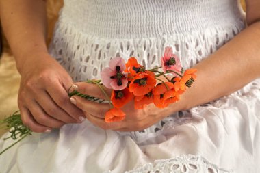 Beyaz elbiseli kadın elinde patlamış çiçeklerle ellerini kapatıyordu. Bahar zamanı hayalleri.