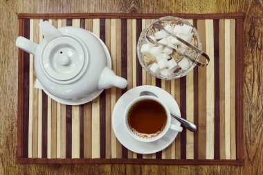 Bir fincan çay, çaydanlık ve şeker kase üstten görünüm ahşap arka