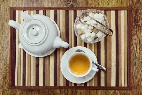 Top view of a cup of green tea, teapot and sugar bowl on a woode — Stock Photo, Image