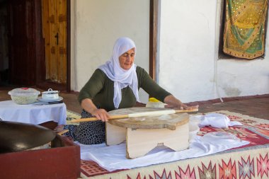 Yaşlı bir Türk kadın geleneksel çanak - pişmiş düz krep fırında tavuklu sağlar.
