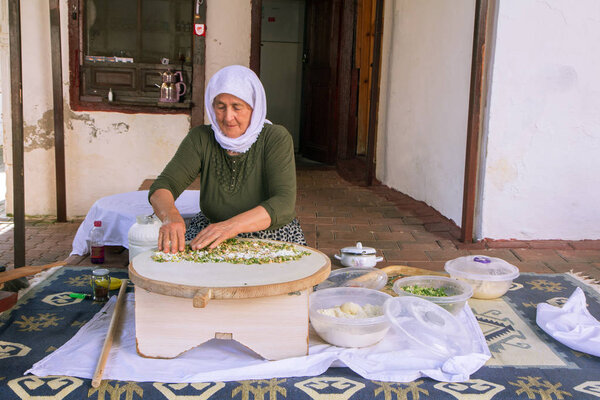 An elderly Turkish woman makes a traditional dish - a baked flat pancake Gozleme