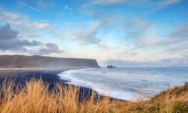 İzlanda 'daki ünlü Kara Kum Sahili Reynisfjara, rüzgarlı sabah, okyanus dalgaları, renkli gökyüzü.