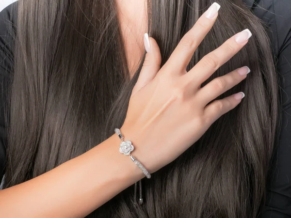 Anillo y pulsera de oro blanco engastados en una mano con manicura francesa, pulsera con flor —  Fotos de Stock