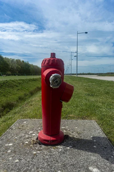 En röd brandpost vy från sidan mot den blå himlen, grönt gräs — Stockfoto