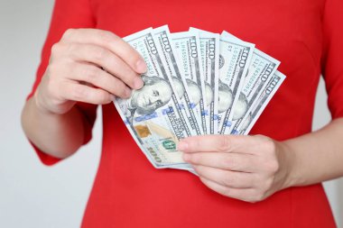 Kırmızı elbiseli kadın dolarları elinde tutuyor, yakın plan. Menajer ya da işkadını parayı sayar, maaş, alışveriş, nakit