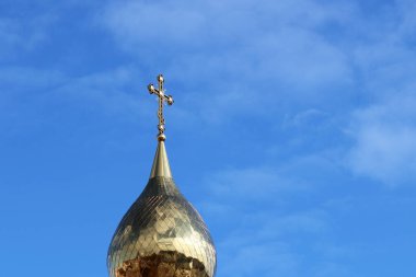 Hristiyan tapınağının altın haçı beyaz bulutlu mavi gökyüzüne karşı. Ortodoks kilise binasının tepesinde, Paskalya kutlaması için arka plan