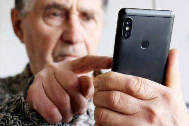 Akıllı telefon kullanan yaşlı bir adam, cep telefonunu erkeklerin elinde tutuyor. Emeklilik, SMS ve sosyal medyada çevrimiçi iletişim kavramı