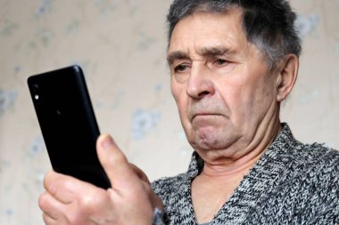 Akıllı telefon kullanan yaşlı bir adam, cep telefonunu erkeklerin elinde tutuyor. Emeklilik, SMS ve sosyal medyada çevrimiçi iletişim kavramı