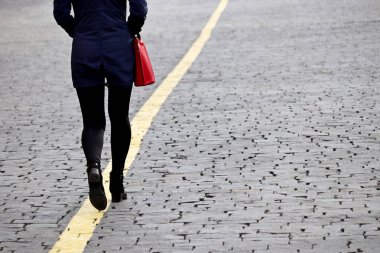 Bahar kıyafetleri içinde ince bir kız sokakta sarı çizgide yürüyor, dikiz manzaralı. Kadın modası kavramı, bir hedef, kariyer ve hayatın hırsı.