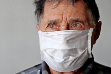 Tıbbi maskeli yaşlı adam üzgün görünüyor. COVID-19 Coronavirus koruması, hastalık, ateş, soğuk algınlığı ve grip kavramı