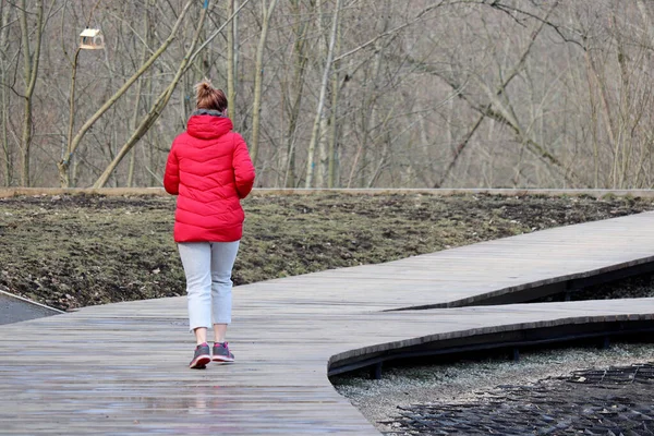 穿着红色夹克的女孩在春天公园里跑 后视镜 运动的概念 女跑步者 在寒冷季节瘦身 — 图库照片
