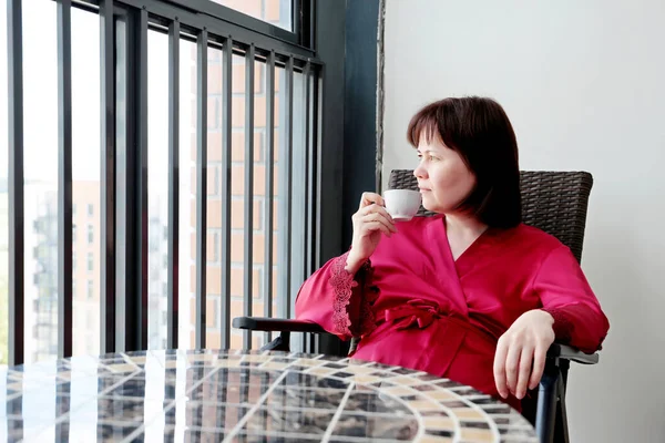 Kobieta Czerwonym Jedwabnym Szlafroku Siedzi Filiżanką Kawy Balkonie Koncepcja Cieszenia — Zdjęcie stockowe