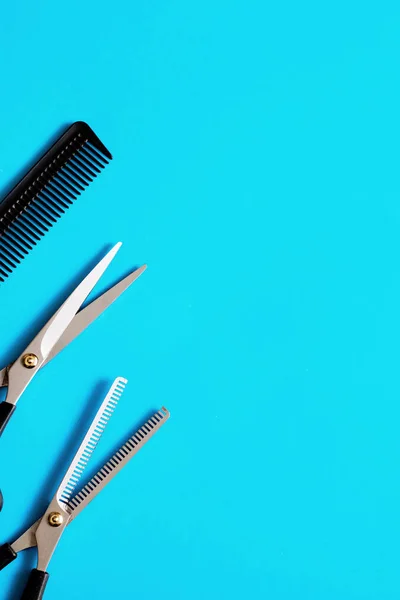 Ciseaux professionnels de coiffeur et peigne sur fond bleu — Photo