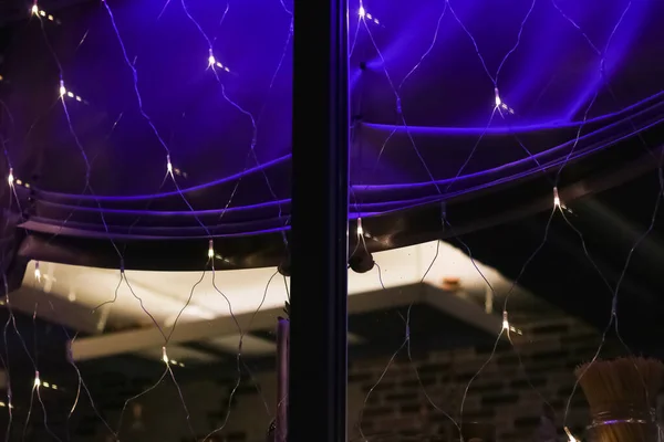 Villanykörték koszorúk az ablakon a sötétben — Stock Fotó