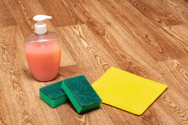 Cleaning agent, sponge and yellow rag on wooden floor — Stock Photo, Image