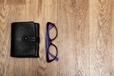 Siyah cüzdan ve gözlükler ahşap bir masada, kopyalama alanı