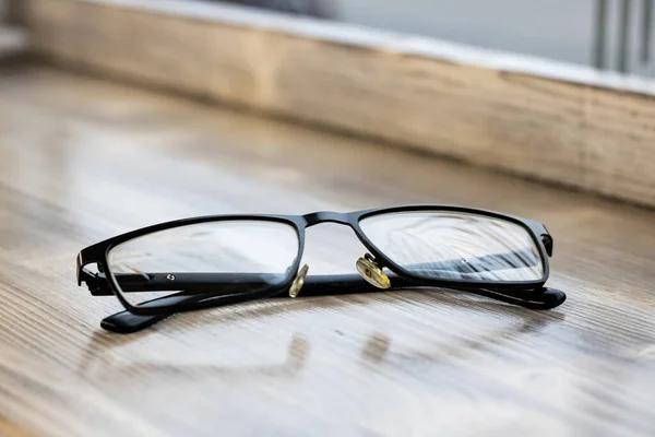 Black glasses on a wooden table closeup — Stockfoto