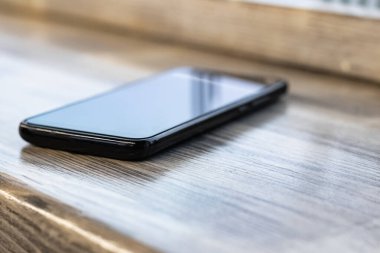 Ahşap masadaki cep telefonu. Yakın plan.