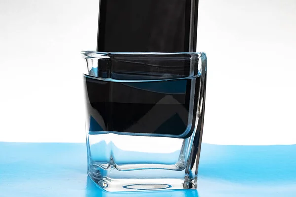Telefone celular em um copo com água — Fotografia de Stock