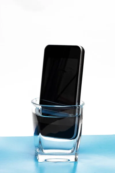 Мобильный телефон в стакане с водой — стоковое фото