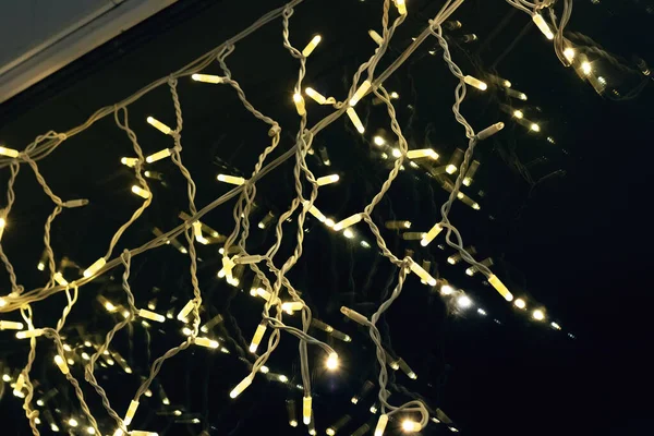 Желтые луковицы новогодней гирлянды на окне — стоковое фото