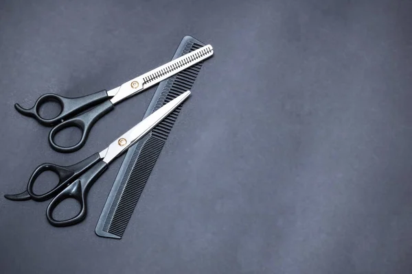 Hairdressing scissors and comb on gray background