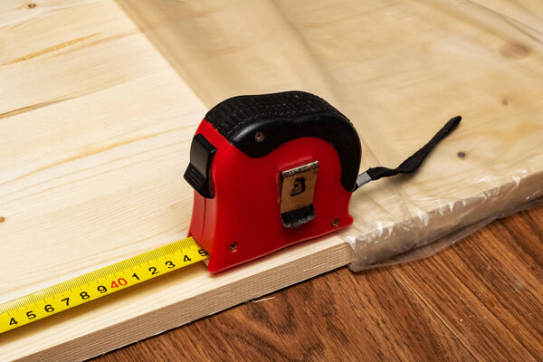 Measuring a wooden board with a tape measure