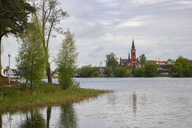 Red catholic church on the river in spring