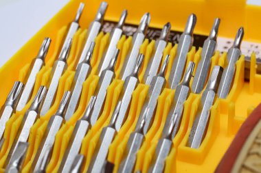 Screwdriver bits in a yellow plastic container close up