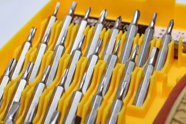 Screwdriver bits in a yellow plastic container close up