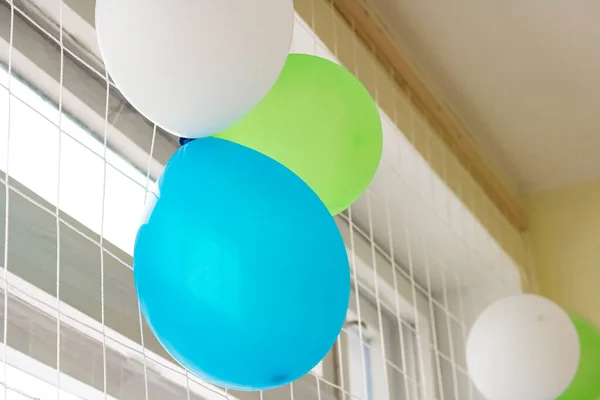 Green, blue and white balloons on the window close up