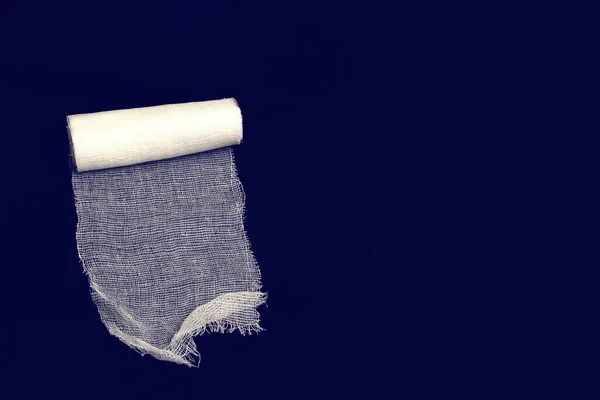 Coil of white bandage on a blue background close up