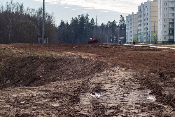 Sand construction site, pit and tractor in sunlight near forest