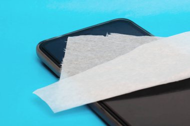 Mavi arkaplanda cep telefonu ve dezenfektan var.