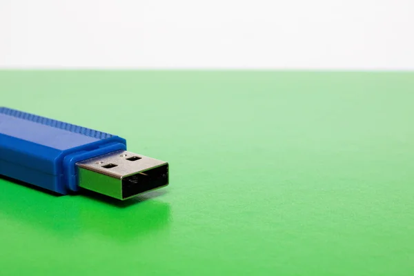 Blue usb flash drive on bright green background, copy space