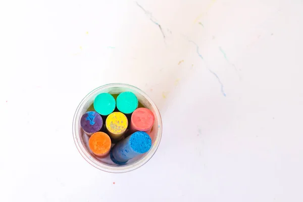 Multicolored crayons in packaging on a white background top view