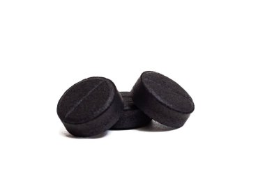 Beyaz arka planda izole edilmiş üç siyah kömür tableti.