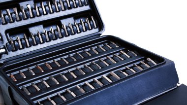 Beyaz zemin üzerinde izole edilmiş tornavida parçaları olan siyah plastik kutu